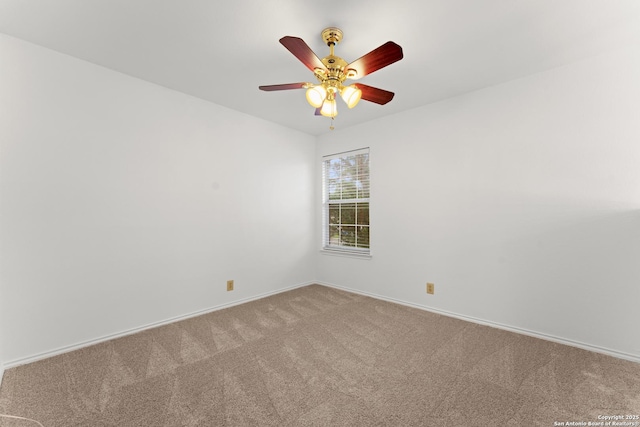 carpeted spare room featuring baseboards and a ceiling fan