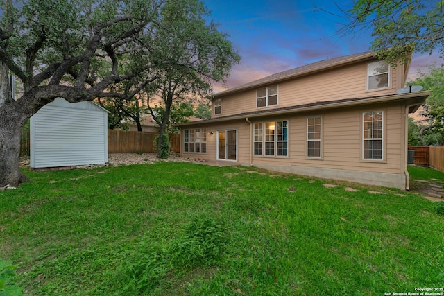 rear view of property featuring a storage shed, an outbuilding, a yard, and a fenced backyard