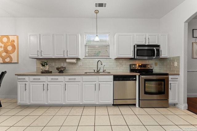 kitchen with decorative backsplash, visible vents, a sink, stainless steel appliances, and white cabinetry