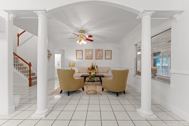 living room with crown molding, ceiling fan, arched walkways, stairs, and light tile patterned floors