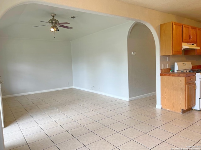 interior space featuring ceiling fan, arched walkways, gas range gas stove, light tile patterned floors, and under cabinet range hood