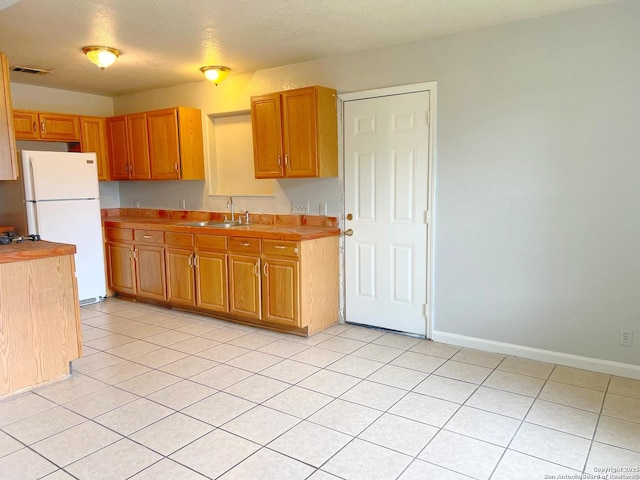 kitchen featuring visible vents, a sink, light countertops, baseboards, and freestanding refrigerator