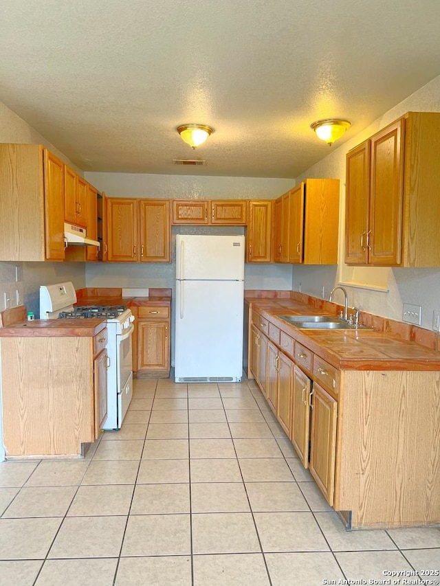 kitchen with a textured ceiling, visible vents, light tile patterned floors, under cabinet range hood, and white appliances