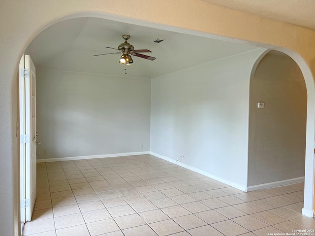 empty room featuring arched walkways, a ceiling fan, visible vents, and light tile patterned floors