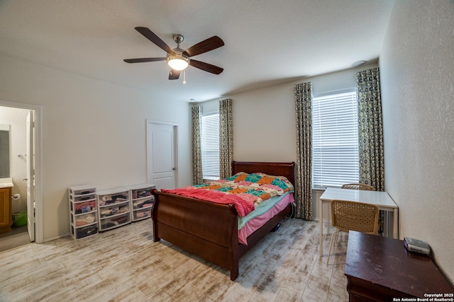 bedroom featuring connected bathroom, ceiling fan, multiple windows, and wood finished floors