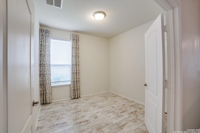 unfurnished room with baseboards, wood finished floors, and visible vents