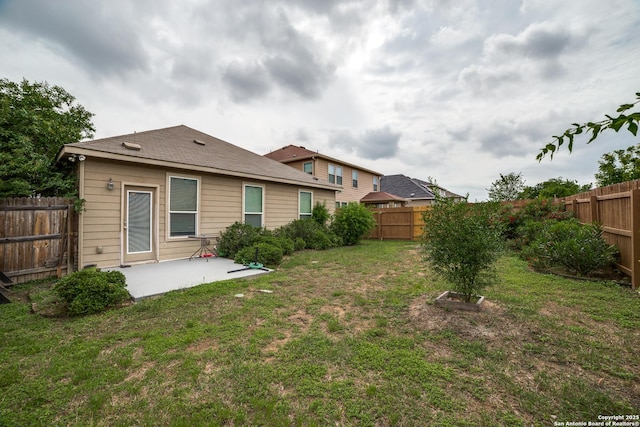 rear view of house featuring a lawn, a patio, and a fenced backyard