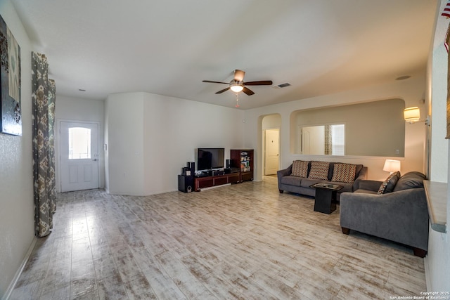 living room with ceiling fan, visible vents, arched walkways, wood finished floors, and baseboards