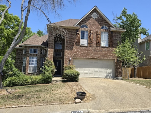 traditional home featuring brick siding, an attached garage, fence, and driveway