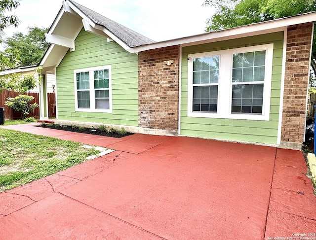 view of front of property with fence, a patio, cooling unit, and brick siding