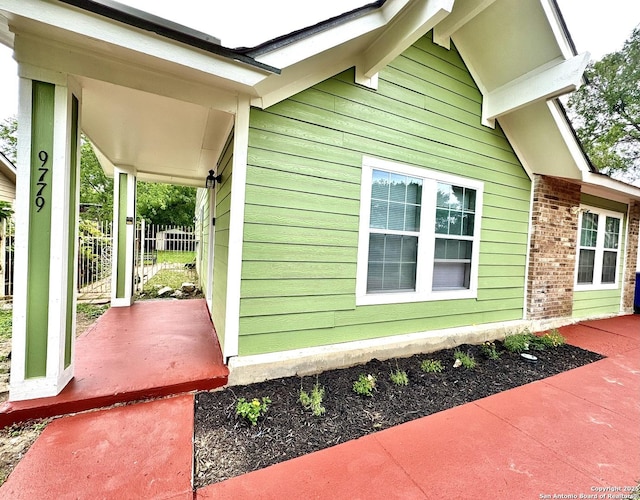 view of side of home featuring a porch and brick siding