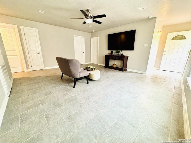living area with recessed lighting, a textured ceiling, ceiling fan, and baseboards