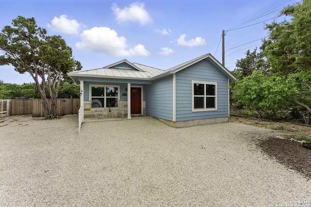 ranch-style home featuring fence, a standing seam roof, and metal roof