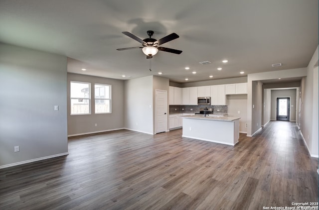 kitchen with a ceiling fan, stainless steel microwave, open floor plan, recessed lighting, and white cabinetry