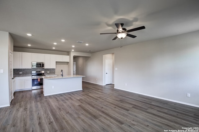 kitchen featuring baseboards, open floor plan, dark wood-style floors, and stainless steel appliances
