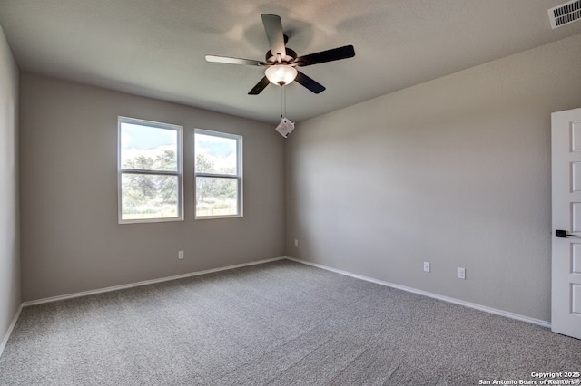 carpeted empty room with baseboards, a ceiling fan, and visible vents