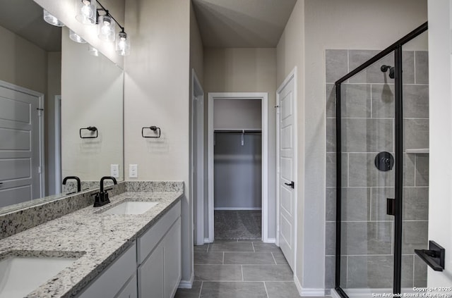 full bathroom featuring a sink, a walk in closet, tile patterned flooring, and a shower stall