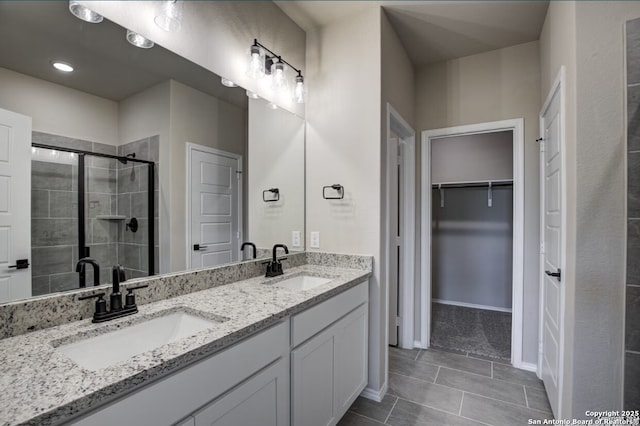 bathroom featuring a sink, a stall shower, double vanity, and a spacious closet