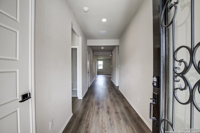 hall featuring baseboards, recessed lighting, and wood finished floors