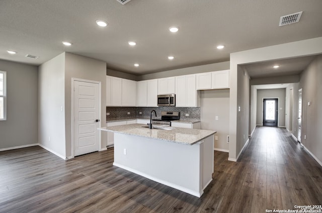 kitchen featuring visible vents, an island with sink, white cabinetry, a sink, and appliances with stainless steel finishes