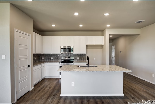 kitchen with stainless steel appliances, light stone counters, a sink, and dark wood-type flooring