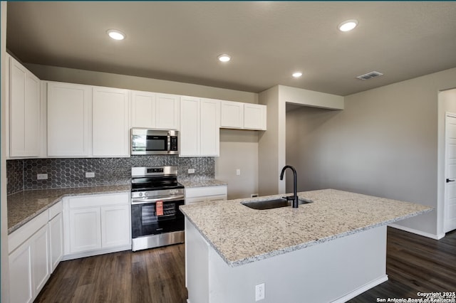 kitchen with visible vents, dark wood-type flooring, light stone counters, a sink, and stainless steel appliances
