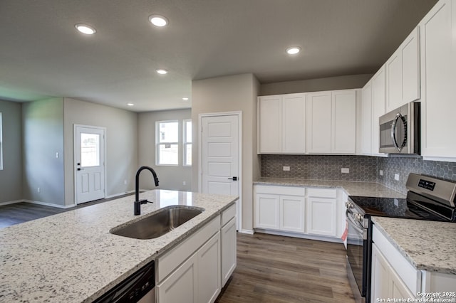 kitchen with decorative backsplash, appliances with stainless steel finishes, a sink, white cabinets, and dark wood-style floors