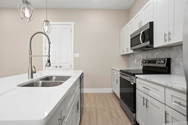 kitchen featuring decorative backsplash, light stone countertops, light wood-type flooring, a sink, and stainless steel appliances