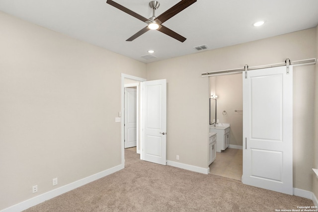 unfurnished bedroom featuring visible vents, recessed lighting, a barn door, and light colored carpet