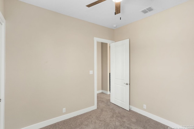 spare room with light colored carpet, baseboards, ceiling fan, and visible vents