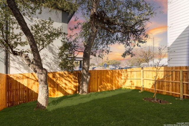 yard at dusk with a fenced backyard
