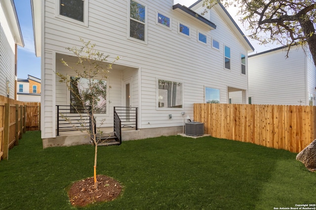 rear view of property featuring a fenced backyard, covered porch, a yard, and central AC unit