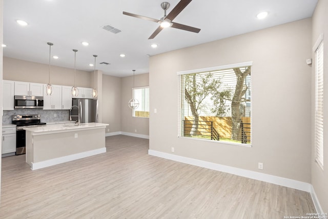 kitchen featuring light countertops, decorative backsplash, stainless steel appliances, and light wood-type flooring