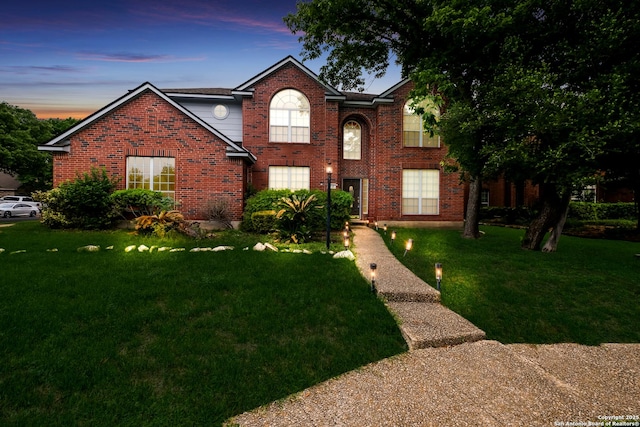 traditional-style home with brick siding and a front lawn