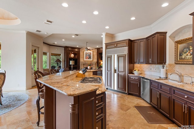 kitchen featuring appliances with stainless steel finishes, a sink, a breakfast bar area, backsplash, and visible vents