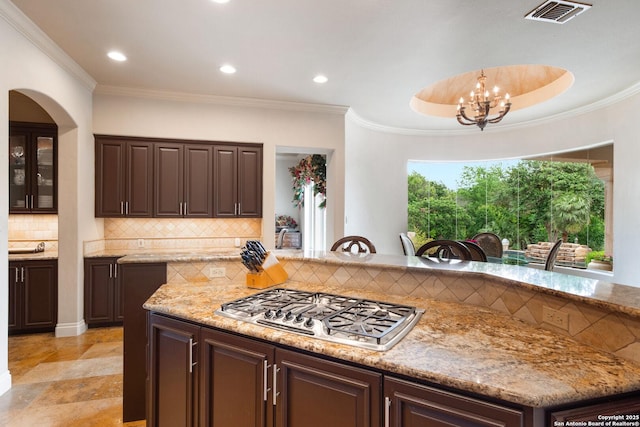 kitchen featuring an inviting chandelier, dark brown cabinetry, visible vents, tasteful backsplash, and stainless steel gas stovetop