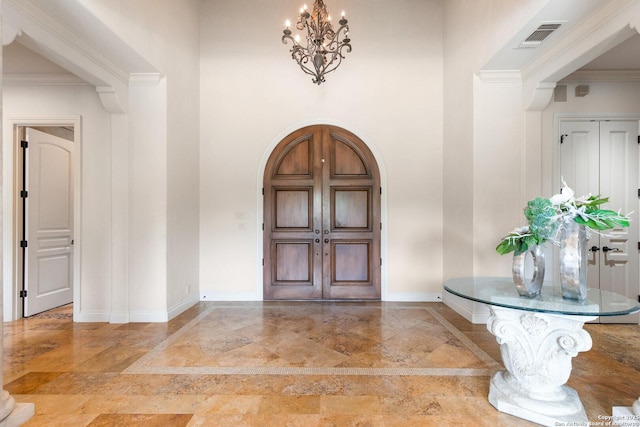 entrance foyer featuring a notable chandelier, arched walkways, marble finish floor, baseboards, and ornamental molding