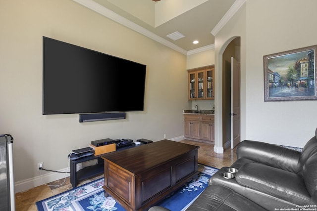 living room featuring wet bar, visible vents, crown molding, arched walkways, and baseboards