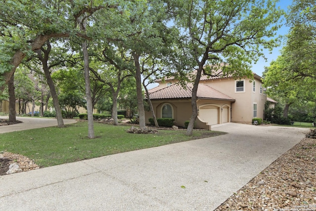 mediterranean / spanish home with a front lawn, stucco siding, concrete driveway, an attached garage, and a tile roof
