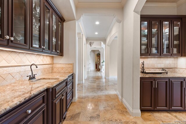 bar with arched walkways, baseboards, decorative backsplash, and a sink