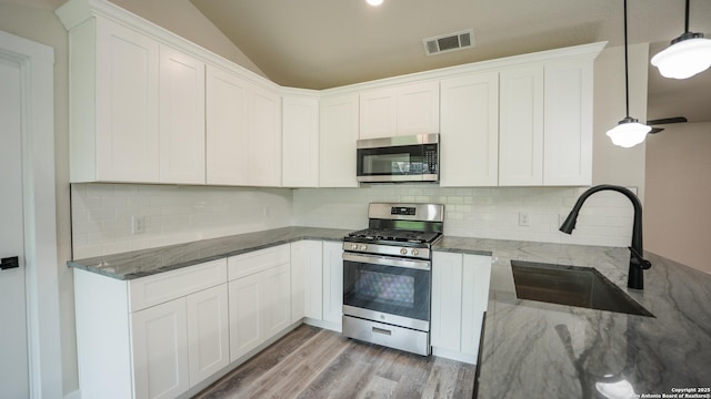 5806 Gillis, San Antonio, TX 78240 - kitchen with a sink, dark stone countertops, lofted ceiling, stainless steel appliances, and white cabinetry