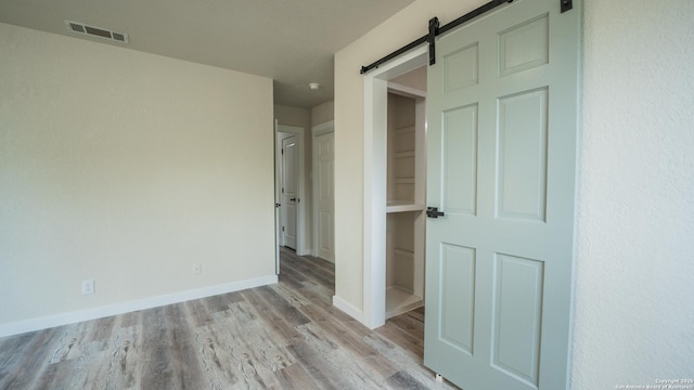 5806 Gillis, San Antonio, TX 78240 - unfurnished bedroom with baseboards, visible vents, a barn door, and light wood-type flooring