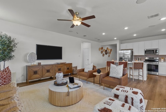 living area featuring ceiling fan, light wood-style flooring, recessed lighting, baseboards, and visible vents