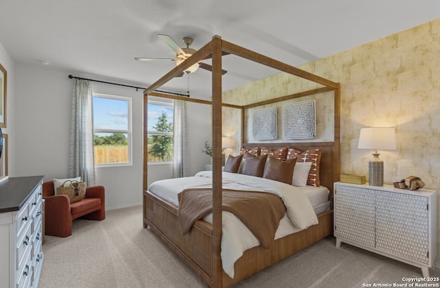 bedroom with a ceiling fan, baseboards, and light carpet