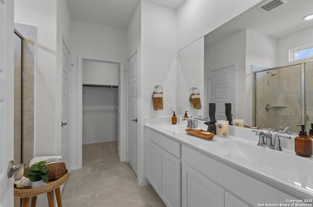 full bathroom featuring a walk in closet, visible vents, a shower stall, and a sink