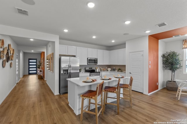 kitchen featuring light countertops, stainless steel appliances, visible vents, and light wood finished floors