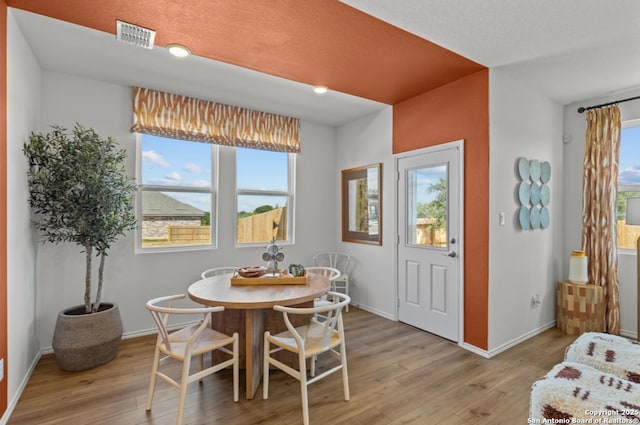 dining room with baseboards, visible vents, and light wood-type flooring