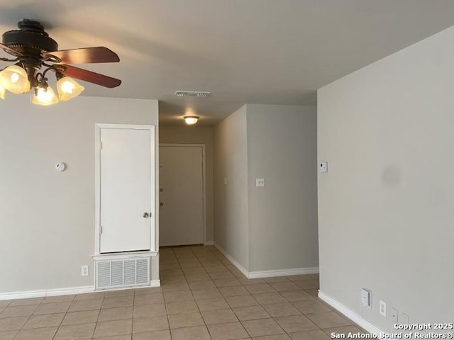 empty room featuring light tile patterned floors, baseboards, a ceiling fan, and visible vents