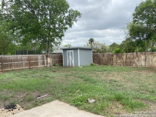 view of yard featuring a storage unit, a fenced backyard, and an outbuilding