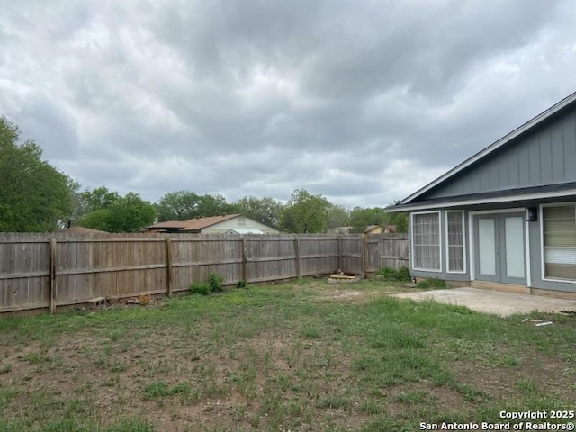 view of yard with a fenced backyard and french doors